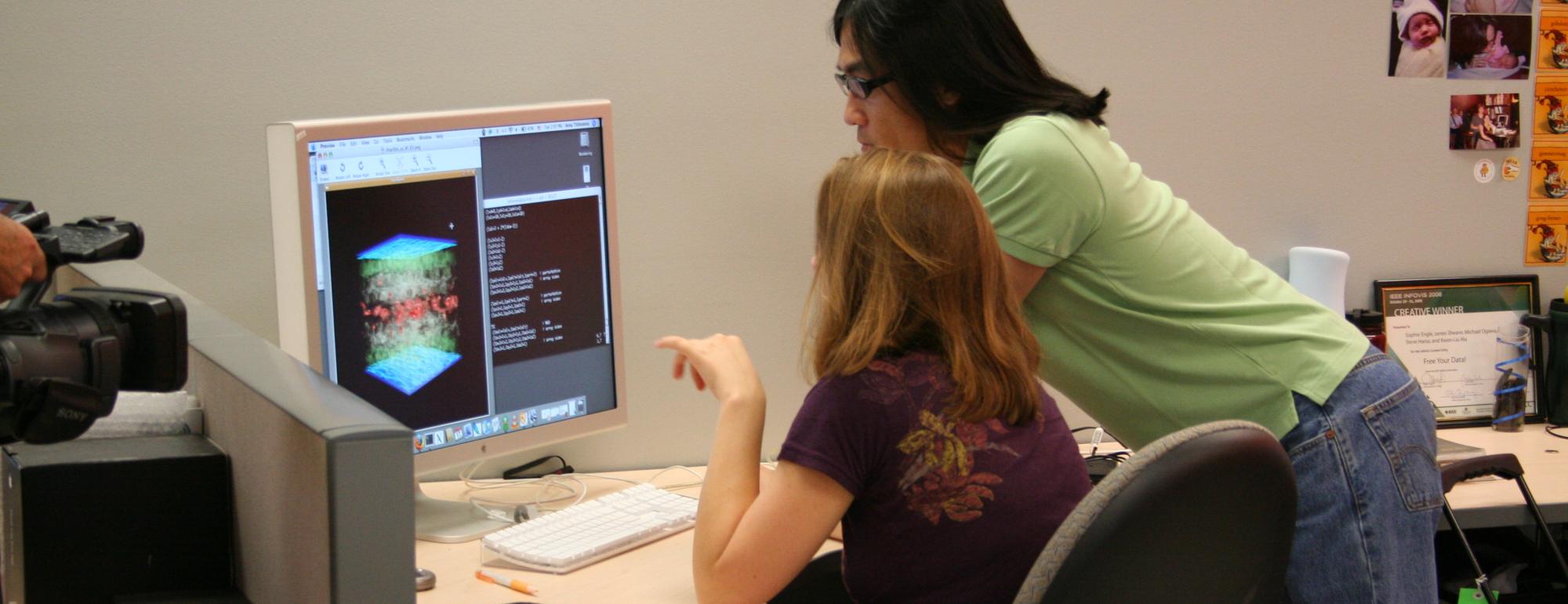 Two people at a desk looking at a computer
