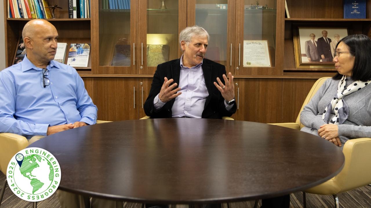 Three people amidst conversation sit behind a round table