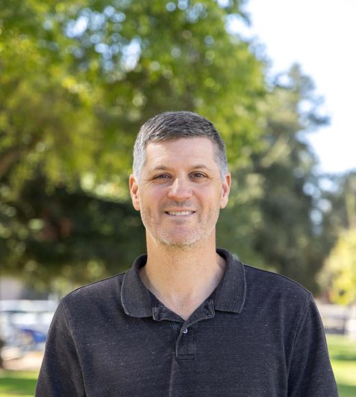Associate Professor of Computer Science Sam King wearing a black polo shirt in front of a natural background