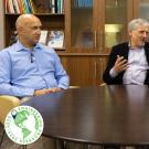 Three people amidst conversation sit behind a round table